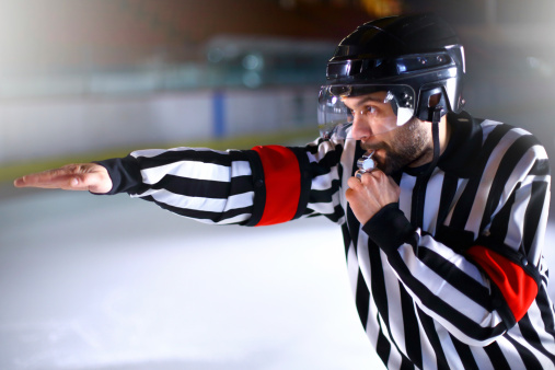 Closeup of ice hockey referee calling a goal.