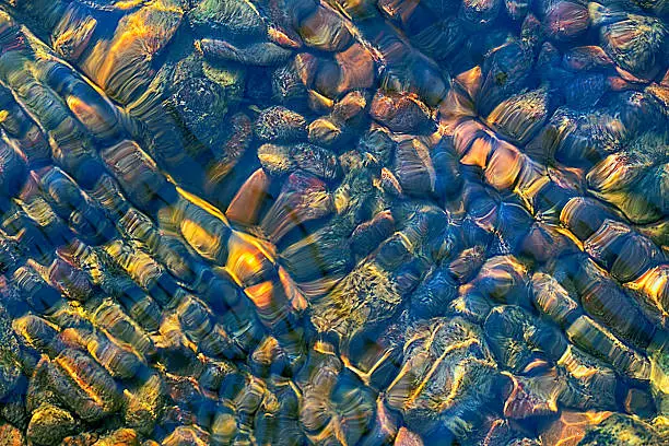 Beautiful colorful stones under flowing water of river