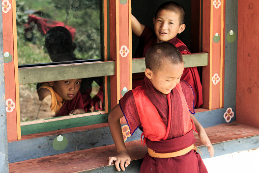 Punakha, Bhutan - August 2, 2014: Young monks relax by a window of a temple in Punakha, Bhutan