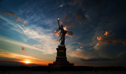 Statue of Liberty on the background of sunrise and cloudy sky