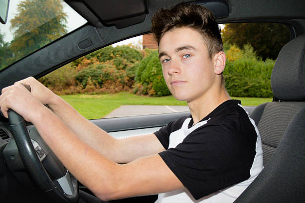 Teen Boy Sitting in Driver's Seat Teenage boy sitting in a right hand driver car's driver's seat teenager boy driving stock pictures, royalty-free photos & images