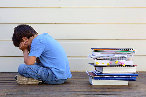 Learning Difficulties A young boy sad to have so much work. schoolyard photos stock pictures, royalty-free photos & images