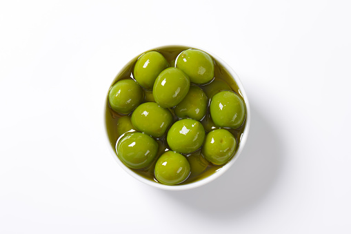 Bowl of green olives in oil