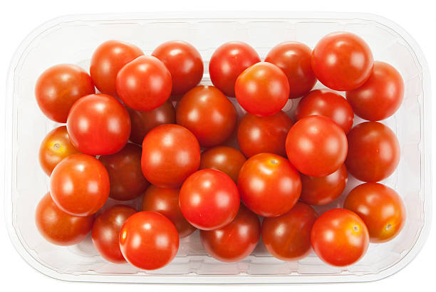 Cherry tomatoes in a plastic container on white background Cherry tomatoes in a plastic container on white background grape tomato stock pictures, royalty-free photos & images