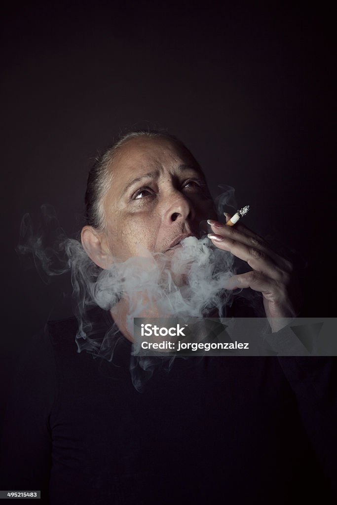 Senior lady smoking Senior lady enjoying a cigarette. A bit of noise added. Addiction Stock Photo