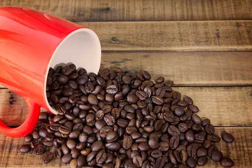 coffee beans and red cup on the wooden table background.