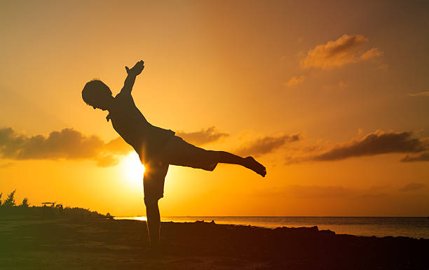istock Silhouette of young man doing yoga at sunset 495225976