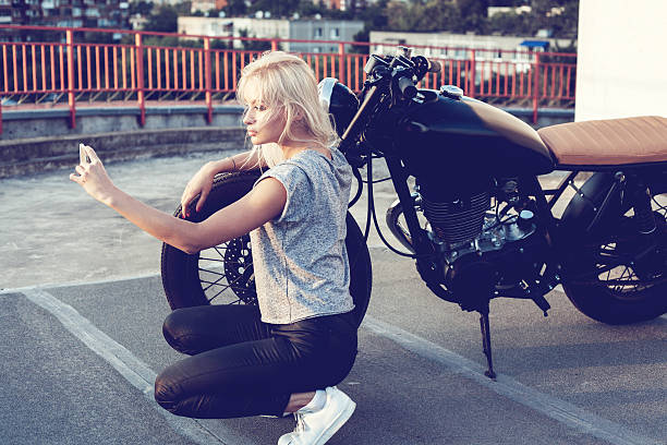 female biker girl making self portrait with vintage motorbike stock photo