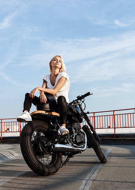 Biker girl sitting on vintage custom motorcycle stock photo