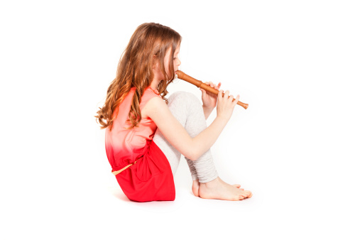 Young teenage girl playing the transverse flute at living room