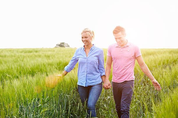 istock Romantic Couple Walking In Field Holding Hands 495235365