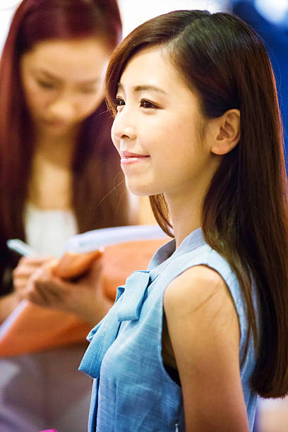 Asian fashion model on a go see. As she strikes a pose, the casting director takes notes in the background.
