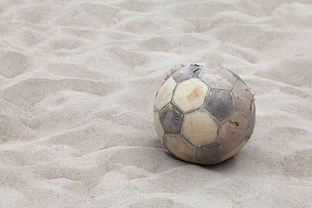istock Old soccer ball on sand beach 495236245