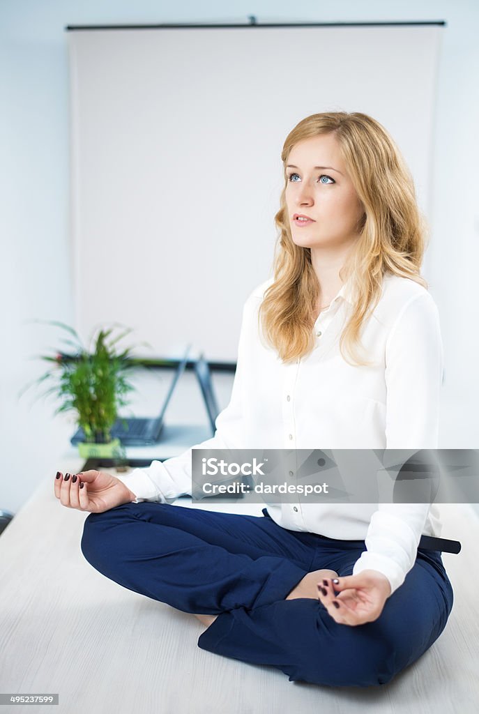 Businesswoman Relaxing Young female office worker sitting in lotus position on top of desk at office 20-29 Years Stock Photo