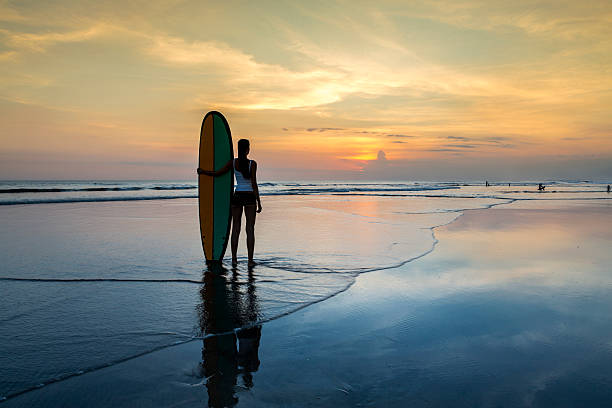 istock Woman with surf board on the beach at sunset 495238201