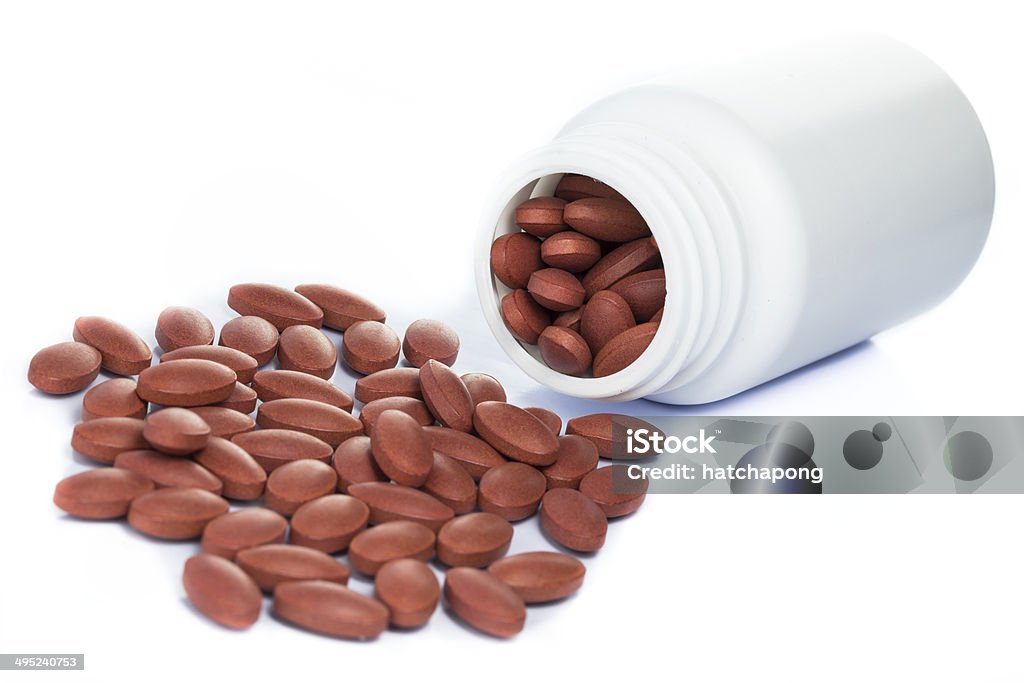 Red pills spilling out of a medicine bottle Red pills spilling out of a medicine bottle isolated on white background Accessibility Stock Photo