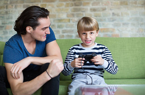 istock Young man and little boy playing video game at home 495242406