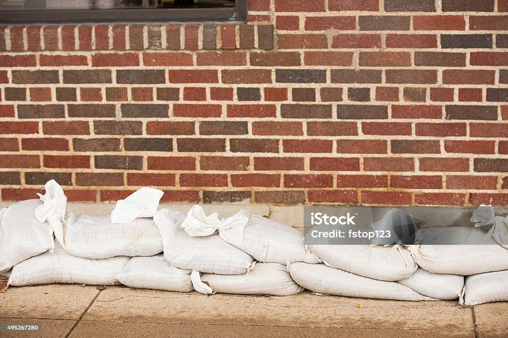 Natural disasters. Flooding. Sandbags line building wall. Natural disasters. Sandbags line the side of a brick building in anticipation, preparation of the rising flood waters caused by recent severe thunderstorms in Texas, USA.  Floods. Flood Stock Photo