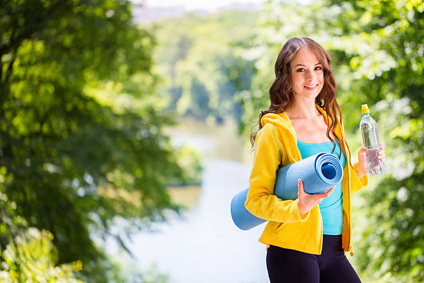 jovem e bela mulher segurando um tapete de yoga e garrafa de água. - teenage girls ideas blue yellow - fotografias e filmes do acervo