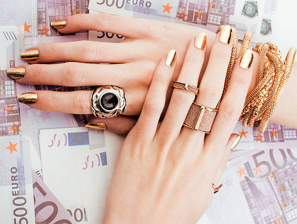 hands of rich woman with golden manicure and many jewelry stock photo