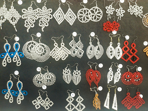 Ljubljana, Slovenia - September 27, 2015: White, red and blue earrings made of cotton lace of different patterns on black background on sale at Sunday flea market along Ljubljanica river in center of the city. Close up. 