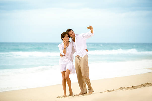 istock couple on the beach and taking a selfie 495272010