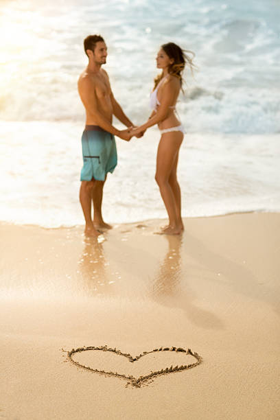 istock happy couple with draw heart on sandy beach 495273812