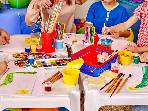 istock Kids hands holding colored paper and glue on table in 495273932