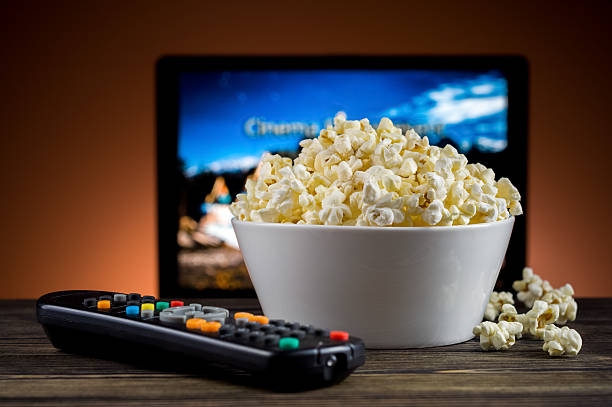 popcorn und eine fernbedienung für den fernseher hintergrund - movie time stock-fotos und bilder