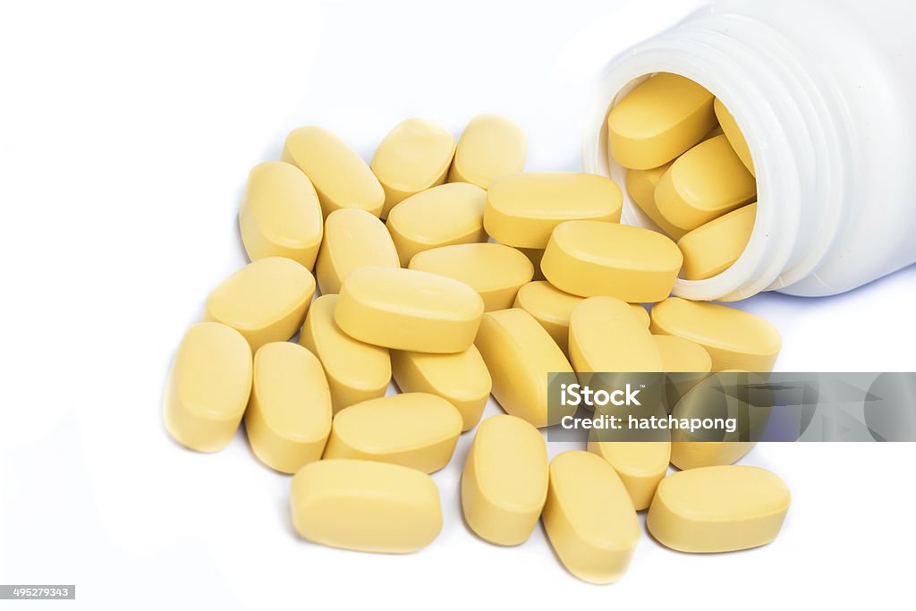 Yellow pills spilling out of a medicine bottle Yellow pills spilling out of a medicine bottle isolated on white background Accessibility Stock Photo