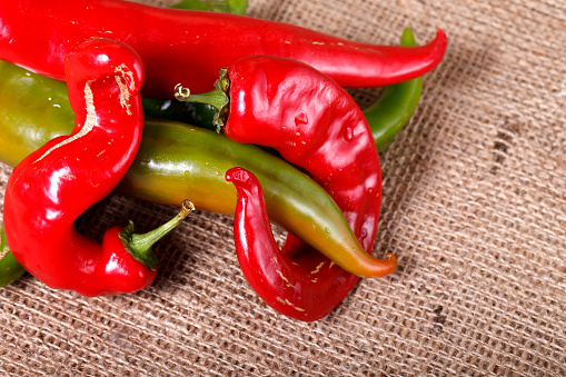 Fresh chili peppers in basket on wooden background