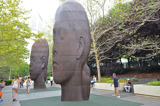 Chicago, USA - August 13, 2015: People next to two of the thin head sculptures in Millennium Park, Chicago, USA. By Jaume Plensa, the statues were installed in 2014 to mark the 10th anniversary of the Park.