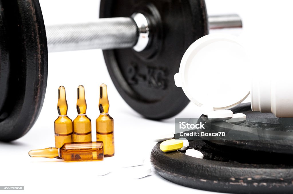 Sport doping and drug abuse Pills and phials of doping substances used in sport. Handle and weights in the background and foreground. 2015 Stock Photo