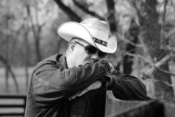 istock Black & White Image of Cowboy Leaning on Fence 495292500