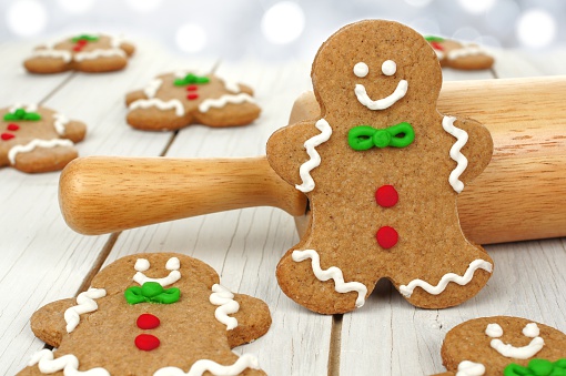 Homemade Christmas gingerbread men with rolling pin on white wood