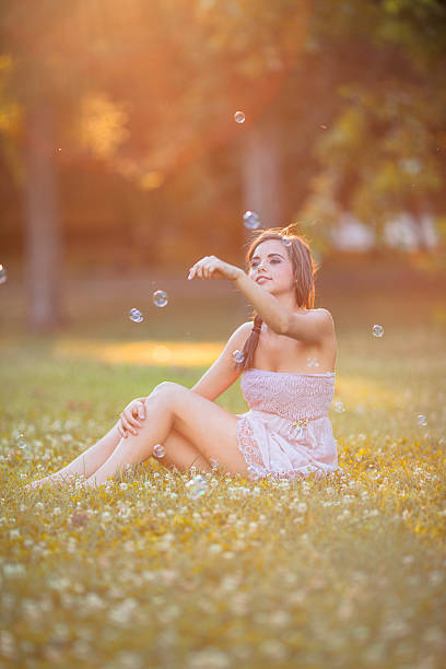 istock woman blowing bubbles outdoors 495306119
