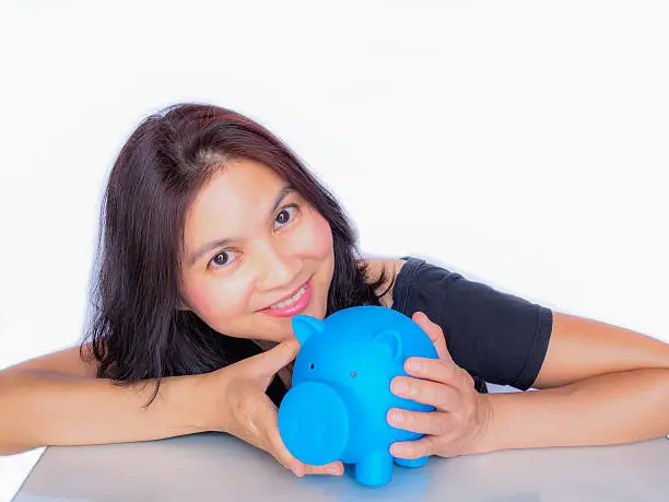 Photo of Asian woman holding piggy bank, thinking about her money