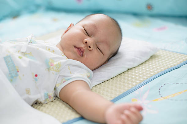 istock Asian baby sleeping white bed linen. 495327512