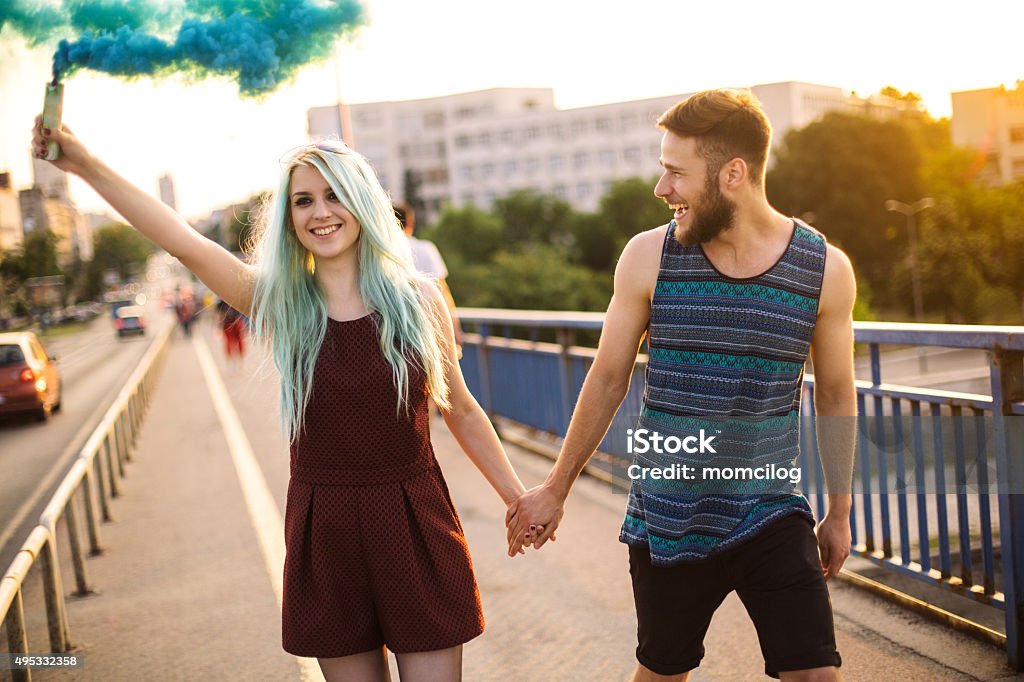 Happy young teenage couple Beautiful teenage couple having fun with colorful blue smoke and smiling Smoke Bomb Stock Photo