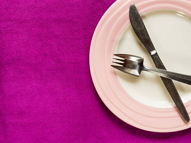istock Empty Plate with fork and knife on purple fabric background 495333687