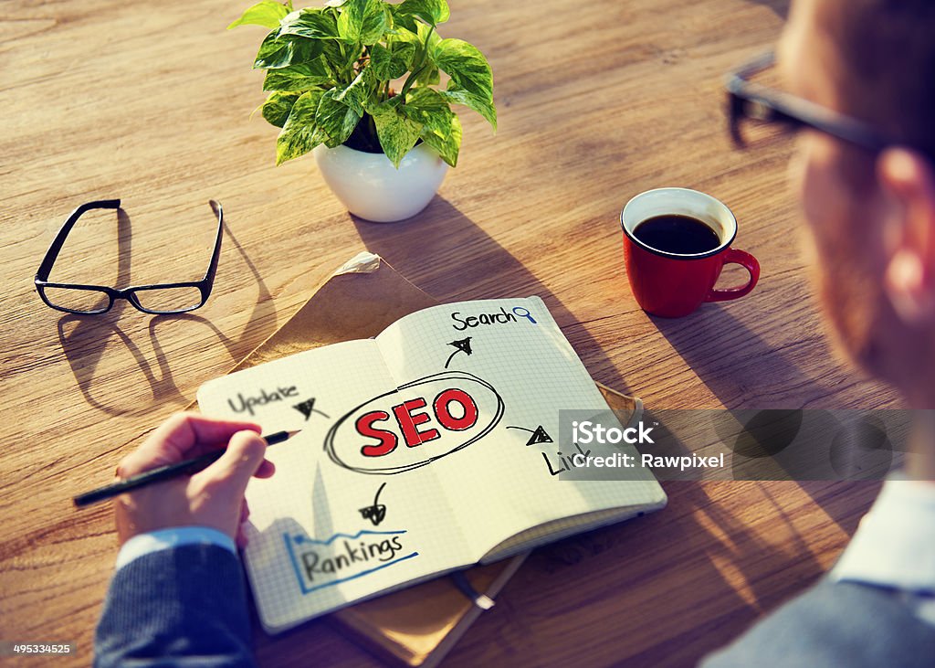 Hipster Writing SEO Concepts on his Note Adult Stock Photo