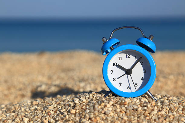 istock Vacation time. Alarm clock on the beach 495341529