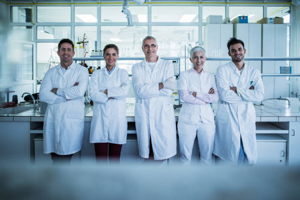 team di scienziati felice con le braccia incrociate in un laboratorio. - research smiling scientist women foto e immagini stock