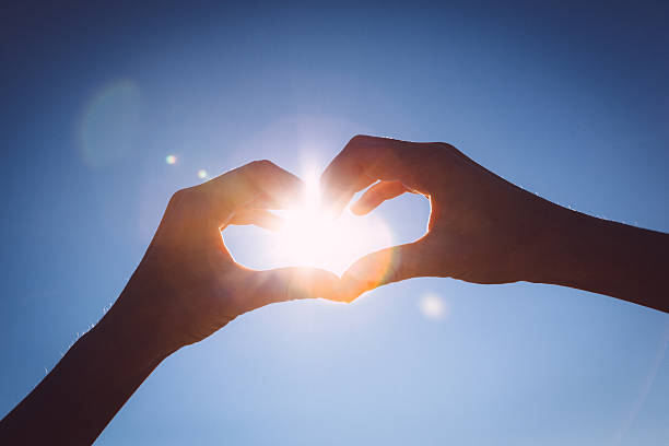 istock Hands making love shape sign on bright blue sky. 495350283