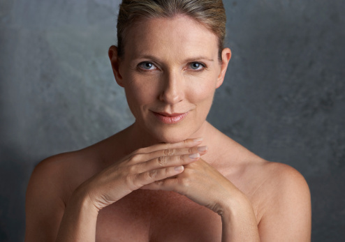 A mature woman with bare shoulders looking at the camera