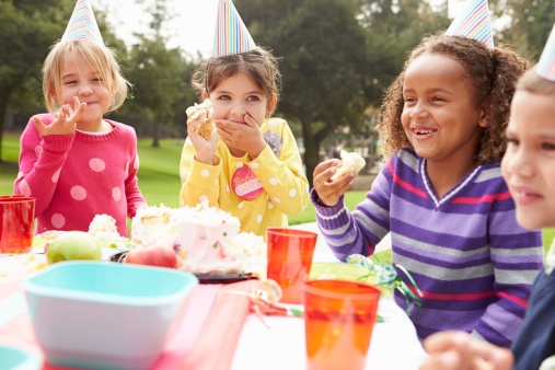 Group Of Children Having Outdoor Birthday Party Eating Birtday Cake