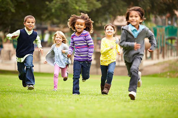 gruppo di bambini piccoli in esecuzione nel parco in direzione della telecamera - child playing running group of people foto e immagini stock