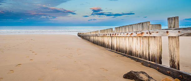 istock Wooden fence on empty beach at sunset 495354757