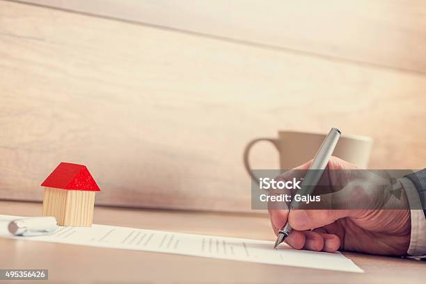 Closeup Of Male Hand Signing Insurance Papers Contract Of House Stock Photo - Download Image Now