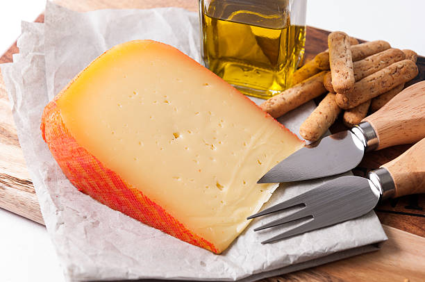 Typical Mahon cheese, Balearic Islands, Spain Wedge of cheese with breadsticks and oil minorca photos stock pictures, royalty-free photos & images
